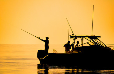 silhouette of sport fishing boat reflecting on calm water - 125861407