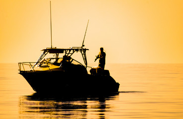 silhouette of sport fishing boat reflecting on calm water