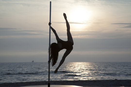 Beautiful silhouette of a woman in splits on pole