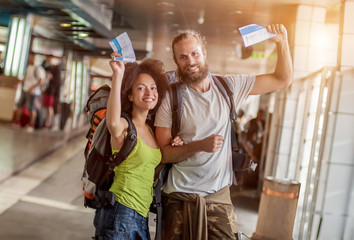 Happy and euphoric couple of backpacker tourists show tickets fo