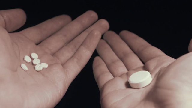 Man choosing between few small pills and one big pill on his hands take them all