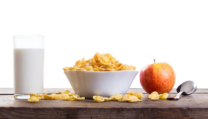 Cornflakes with milk and apple on wooden table