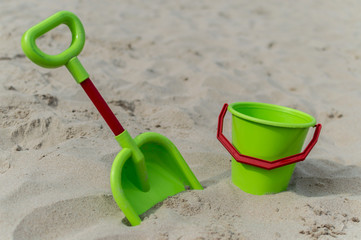 Fototapeta na wymiar View of a green bucket and scoop at the beach with sand in the background