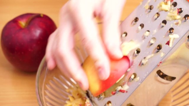 Female hand grating apple for salad. Cooking, food and home concept. 4K ProRes HQ codec