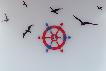 Red blue ship's steering wheel and flying birds -  illustration on wall © Kazick