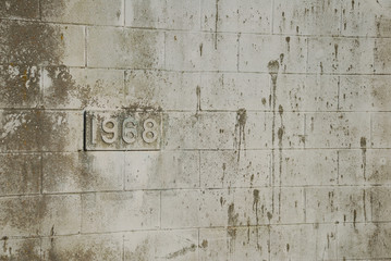 Building's birthdate (1968) on dirty cinderblock wall