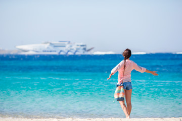 Young girl on the beach background big cruise liner. Woman enjoy her wekeend on one of the beautiful beaches in Greece, Europe.