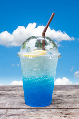 blue lemon soda on wood table with green leaves background, be f