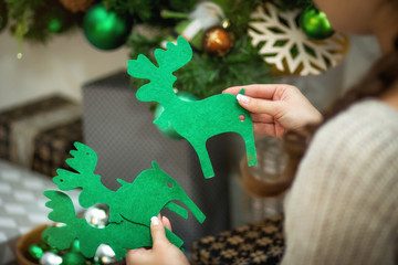 Девушка держит в руках рождественский декор зеленых...
