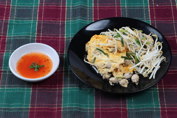 Thai food,Fried egg and oyster with bean sprouts and shallot as Hoi Tod Khai in Thai served with chili sauce.