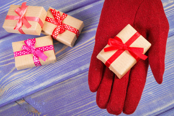 Hand of woman in gloves with gifts for Christmas or other celebration