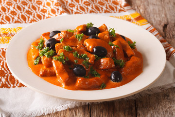 Spanish pieces of pork stewed in a spicy sauce of wine, tomatoes and cream closeup. horizontal