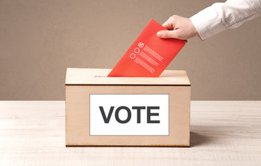 Close up of male hand putting vote into a ballot box