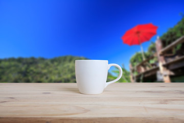 Cup of coffee on a wooden table and nature background.