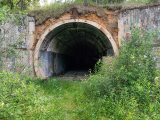 Old abandoned undetected military undeground tunnel storage among wild tall weeds. Kaluzhskaya region, Russia.
