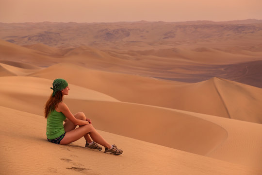 Young woman sitting on sand in a desert near Huacachina, Ica reg