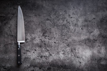 Kitchen knife on concrete or wooden board.