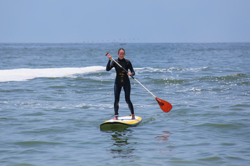 Young woman paddling on a board in Punta Hermosa, Peru
