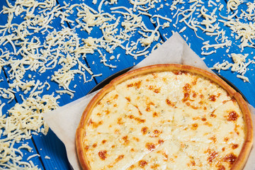 Pizza with three cheeses./Pizza with three cheeses on a wooden board blue.