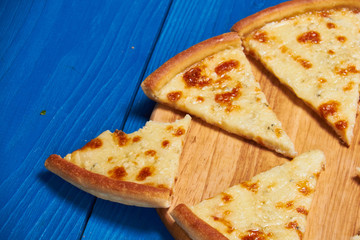 Pizza with three cheeses./Pizza with three cheeses on a wooden board blue.