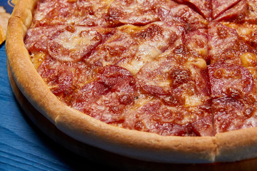 Sliced whole salami pizza./Sliced whole salami pizza on a wooden table.