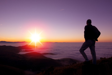 The sun sets behind the mountains in fall