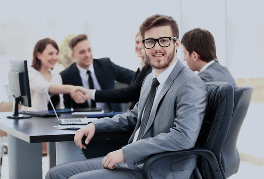 Portrait of mature business man smiling during meeting with colleagues in background