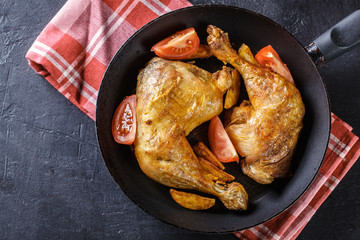 Roasted chicken legs with potato wedges and tomatoes