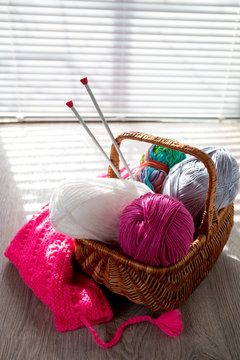 Ball of yarn and knitting needles in basket on a wooden grey table with window light. Close up. Handmade.