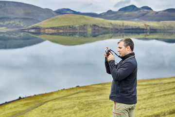 man hiker photographer taking picture on the lake background in Iceland