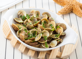 Dish of clams served on a wooden table. © hansgeel