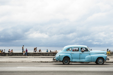 HAVANA, CUBA - MAY 18, 2011: Classic vintage American car serving as taxi drives along the seafront Malecon, a popular place for socializing in Central Havana.
