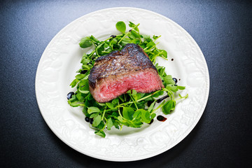 Beef steak sliced Mignon with salad. Served on white plate