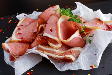 Raw beer bacon slices on crumpled paper which herbs