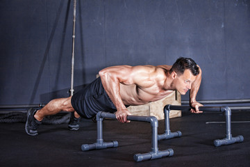 Fototapeta na wymiar Man doing a push-up on one arm in a gym
