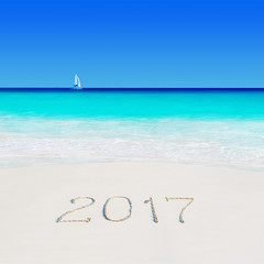 Fototapeta na wymiar Yacht under sail at beach and year 2017 sand caption