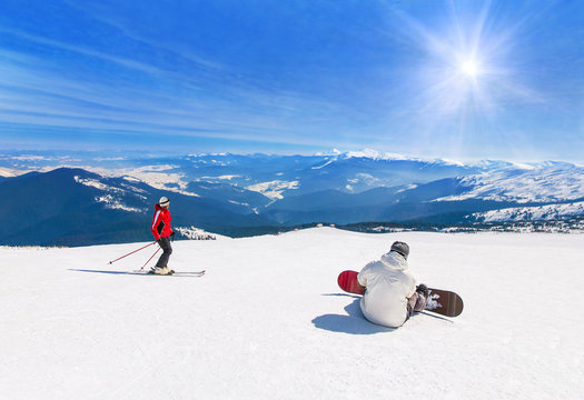 Skier and snowboarder skiing downhill in mountains, winter sport background