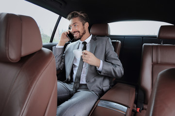 Young businessman having a coffee in his car