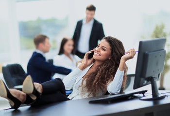 Photo of smiling brunette businesswoman with legs on the desk ph