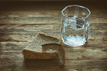 glass of water and hunk black bread - obrazy, fototapety, plakaty