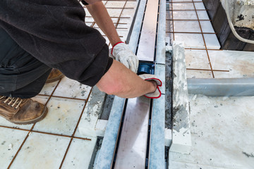 Waterproofing and thermal insulation of a terrace. A bricklayer, over a layer of extruded polystyrene, is installing a drain gully for drainage of a terrace
