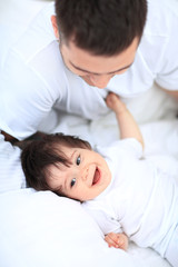 Obraz na płótnie Canvas Baby boy lying on bed, next to his father