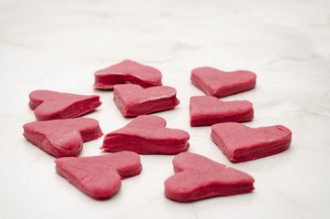 Red hearts of raw beet dough on a white table, side view