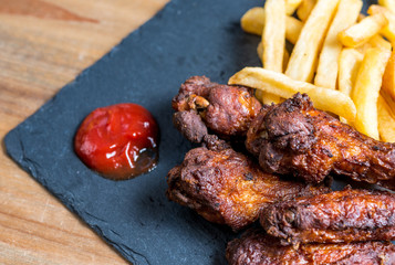 Chicken wings with sauce and golden French fries potatoes
