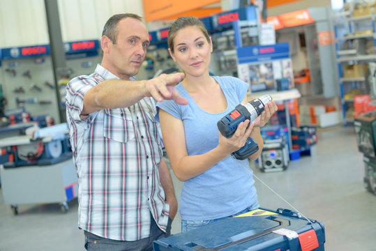 Couple in hardware shop, man pointing