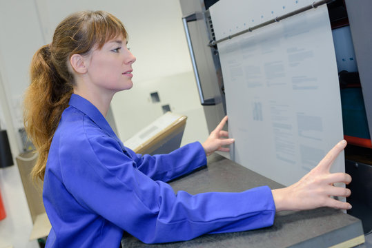 Female worker straightening card in machine
