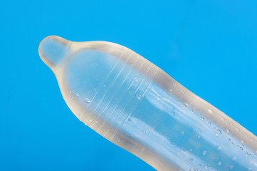 Ribbed and dotted condom full of water isolated on the blue background