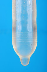 Ribbed and dotted condom full of water isolated on the blue background