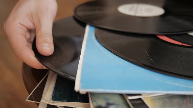 Male hand carefully chooses and pulls favorite retro vinyl record from the LP collection stack.