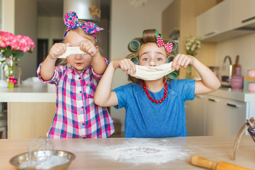 Funny little sisters sculpt and play with a dough on a kitchen
